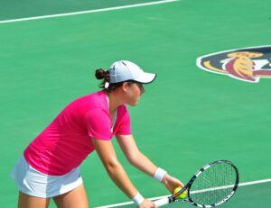 A tennis player serving on a hard court during a match