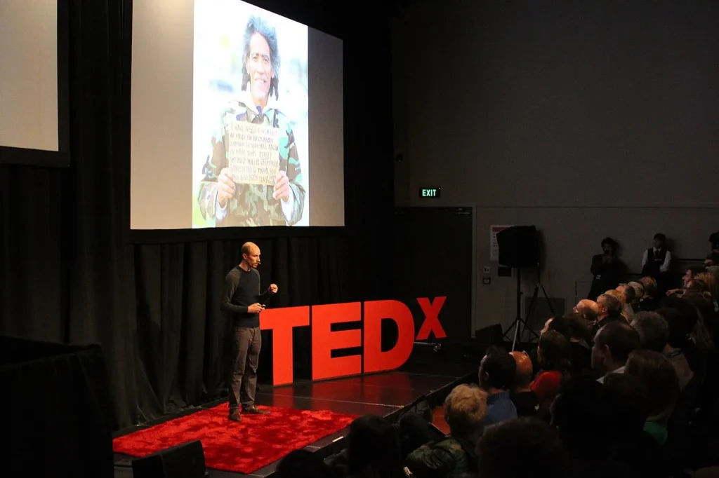 The founder of an online image-sharing community presenting a member's photo on stage at a TEDx event.