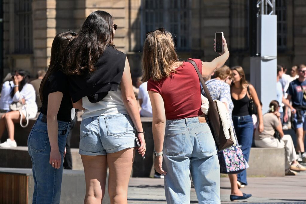 Young people gathered around a smartphone, sharing a moment on social media