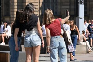 Young people gathered around a smartphone, sharing a moment on social media